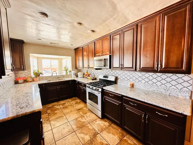 a kitchen with stainless steel appliances granite countertop a stove a sink dishwasher and a microwave
