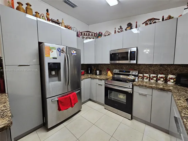 a kitchen with stainless steel appliances granite countertop a refrigerator and a stove top oven