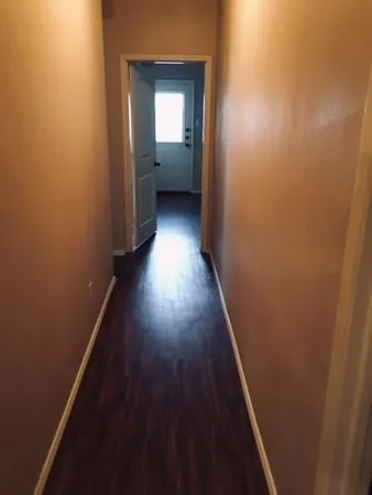 a view of a hallway with wooden floor and a bathroom