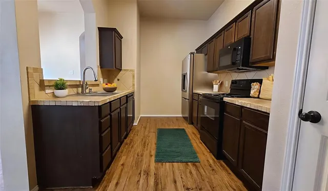 a kitchen with stainless steel appliances granite countertop a refrigerator a stove top oven a sink and dishwasher