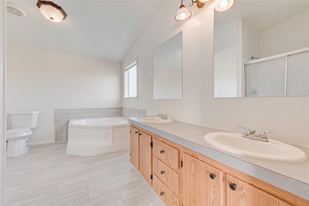817 Kaufman Street Rosser, TX 75158 - Photo 21 of 29 Bathroom featuring a bath, double vanity, a shower stall, and lofted ceiling
