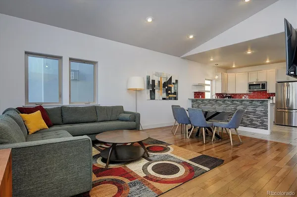 a living room with furniture and a dining table with wooden floor