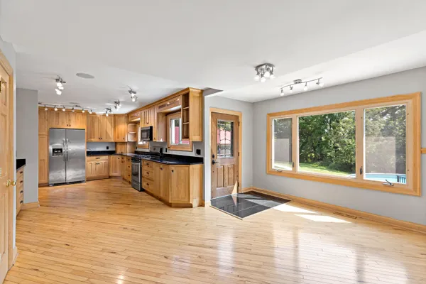 a view of a kitchen with kitchen island a window wooden floor and stainless steel appliances
