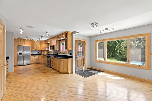 a view of a kitchen with kitchen island a window wooden floor and stainless steel appliances