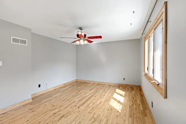a view of empty room with wooden floor and fan