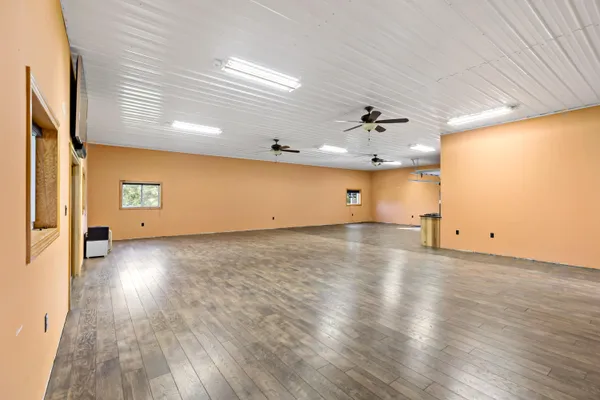 an empty room with wooden floor and a ceiling fan