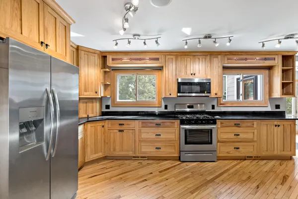a kitchen with stainless steel appliances granite countertop a stove top oven a sink and a refrigerator