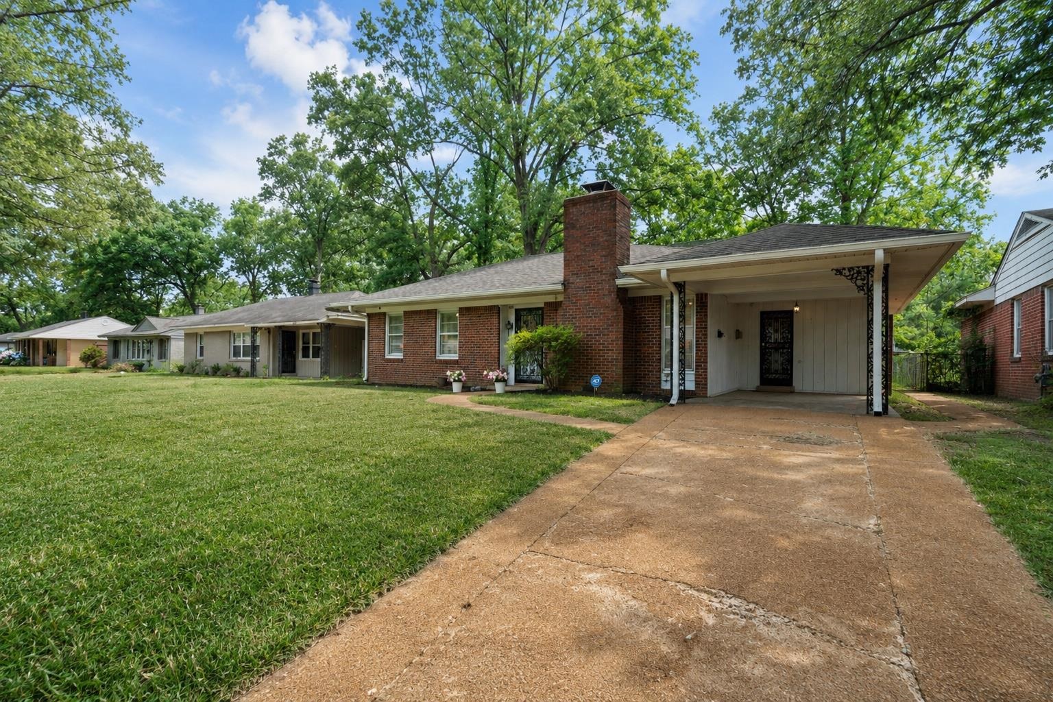 4491 Garnett Road Memphis, TN 38117 - Photo 28 of 32 Brick exterior with a prominent chimney, a covered carport, and a concrete driveway
