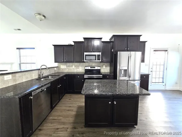 a kitchen with stainless steel appliances granite countertop wooden cabinets a refrigerator and a stove