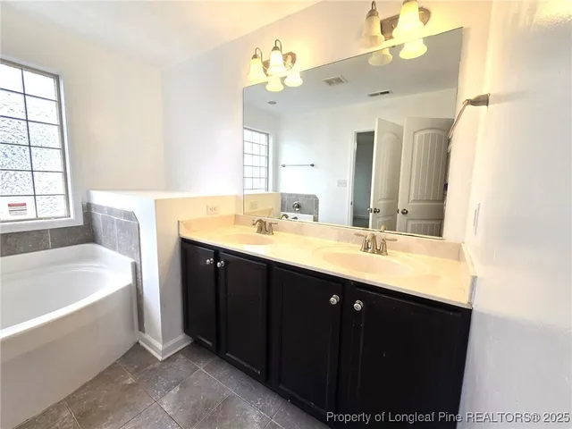 a bathroom with a tub a double vanity sink and a mirror