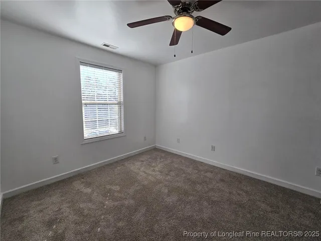 an empty room with a window and a fan
