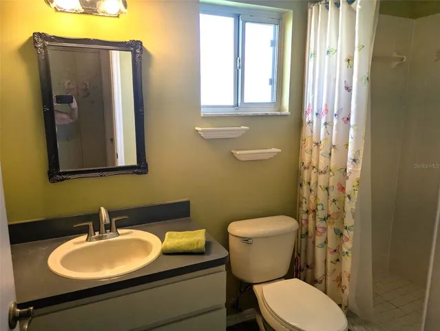 a bathroom with a granite countertop toilet sink and mirror