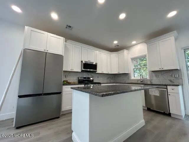 a kitchen with stainless steel appliances granite countertop a refrigerator a sink a stove a microwave and white cabinets