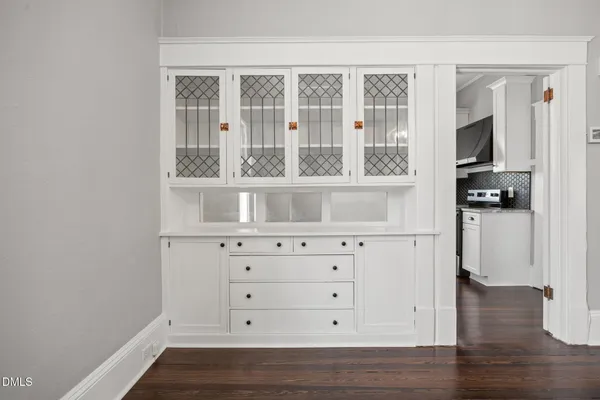 a kitchen with white cabinets and wooden floor