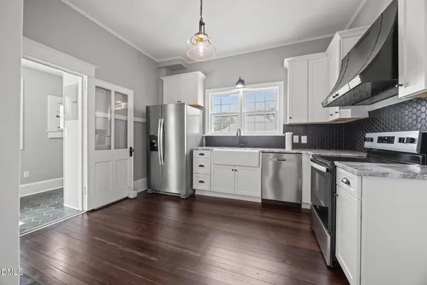 a kitchen with stainless steel appliances white cabinets granite counter tops and a wooden floors