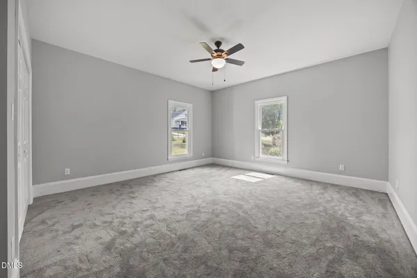 an empty room with wooden floor chandelier fan and windows