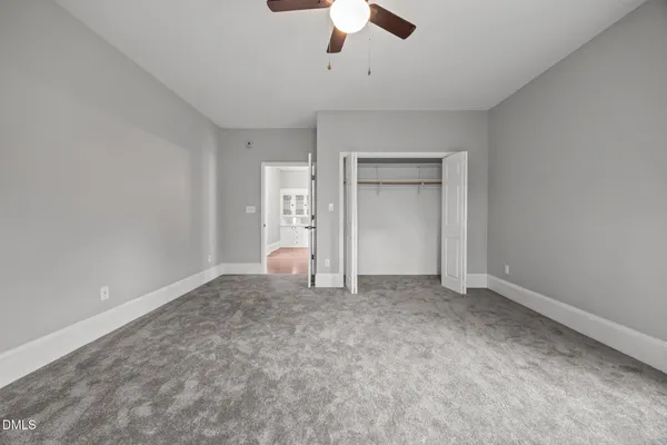 an empty room with wooden floor chandelier fan and windows
