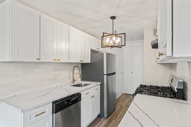 a kitchen with stainless steel appliances a sink a stove a refrigerator and cabinets