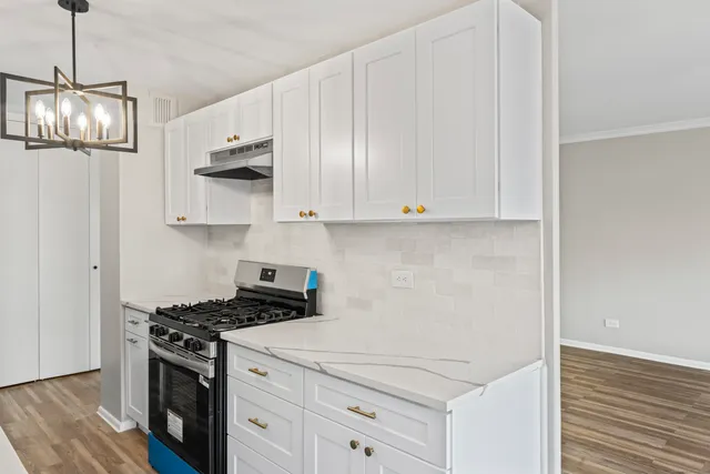 a kitchen with stainless steel appliances granite countertop white cabinets and a stove