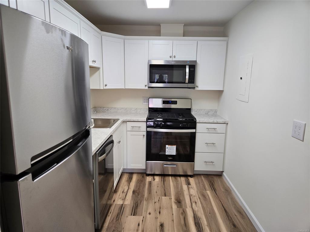 119 Crooked Hill Road, Unit 103 Pearl River, NY 10965 - Photo 14 of 16 Kitchen featuring hardwood / wood-style floors, electric panel, white cabinets, light stone countertops, and stainless steel appliances