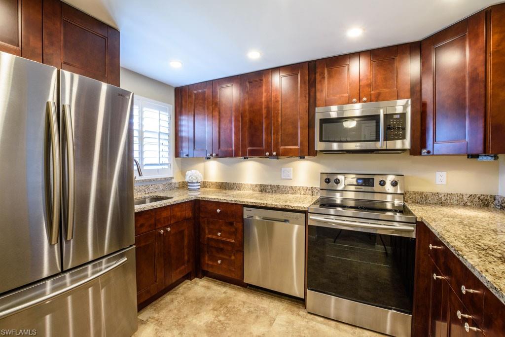 1 High Point Circle West, Unit 203 Naples, FL 34103 - Photo 4 of 31 a kitchen with stainless steel appliances granite countertop wooden cabinets a stove top oven a sink and dishwasher
