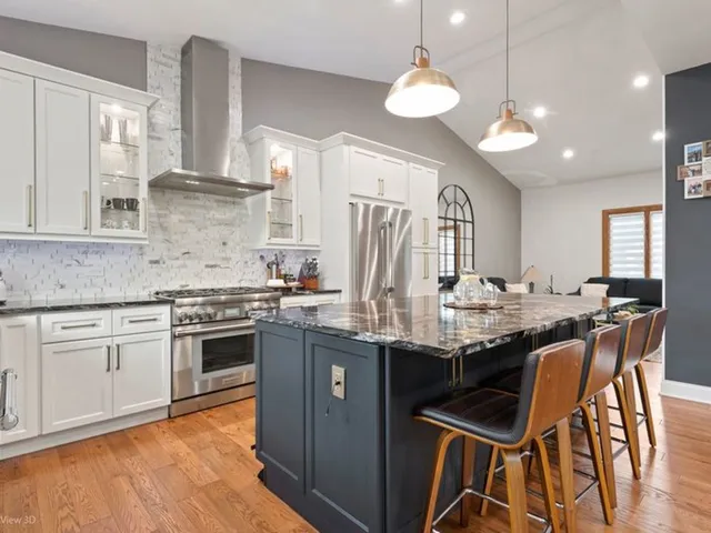 a kitchen with stainless steel appliances granite countertop a stove top oven a sink dishwasher a dining table and chairs with wooden floor