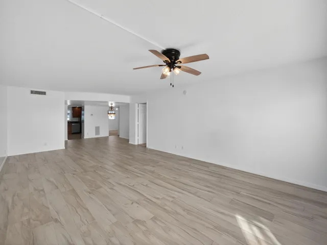 a view of a room with wooden floor and a ceiling fan