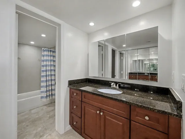 a bathroom with a granite countertop sink a mirror and a shower