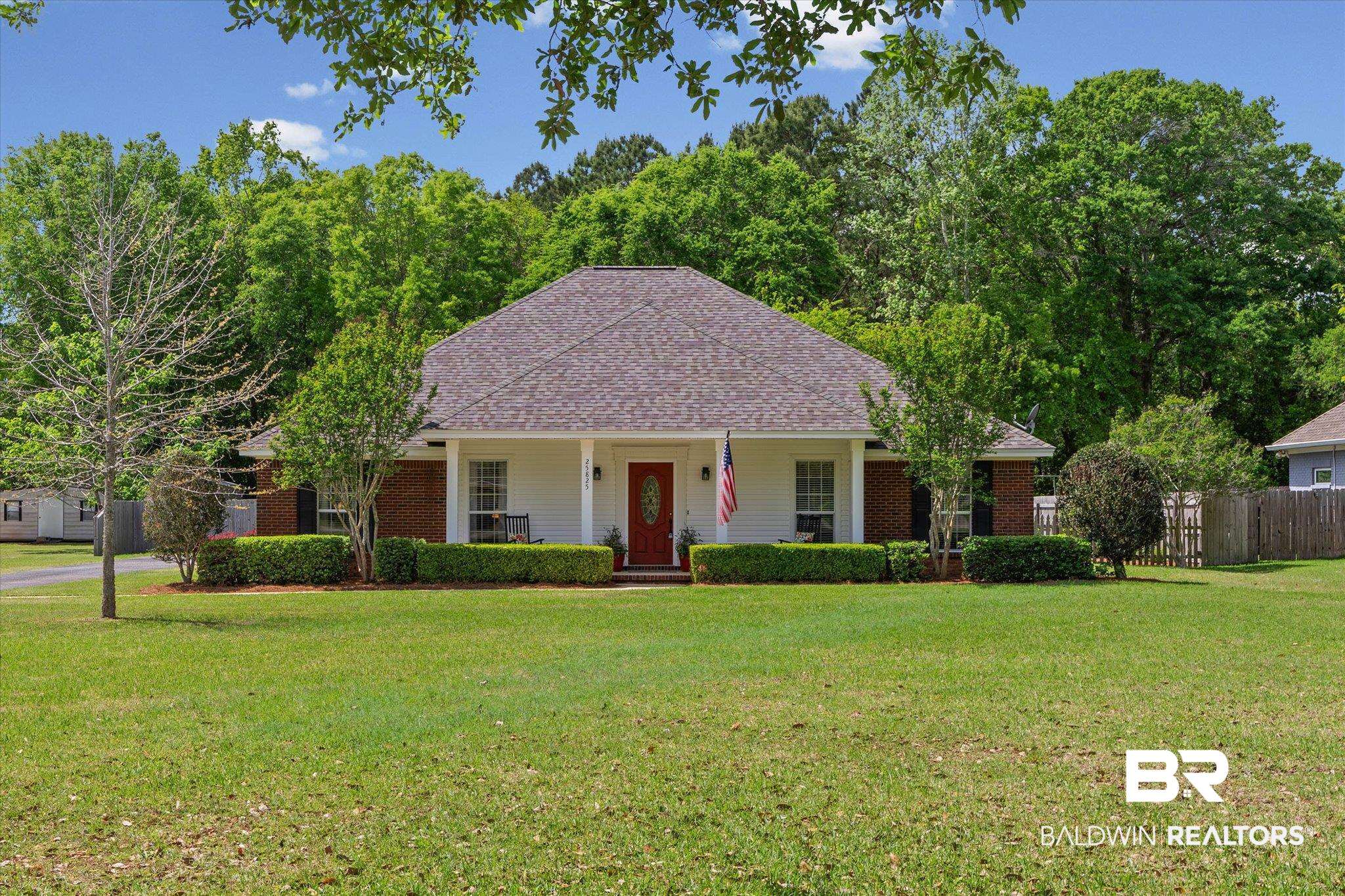 View of front of home with a porch, roof with shingles, and brick siding