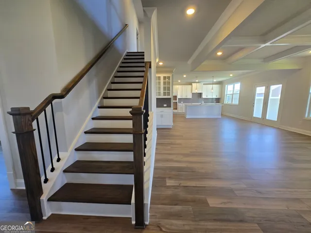 a large kitchen with stainless steel appliances granite countertop a stove a sink a refrigerator and white cabinets with wooden floor