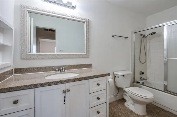 a bathroom with a granite countertop toilet sink and mirror
