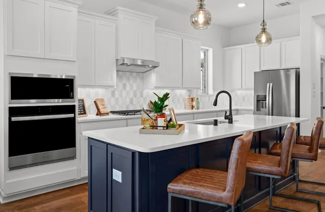 a kitchen with stainless steel appliances a sink a stove a refrigerator and cabinets