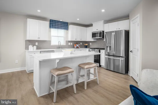 a kitchen with stainless steel appliances a refrigerator a stove a sink and chairs