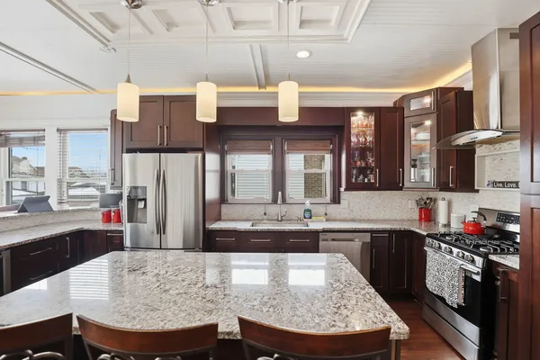 a large kitchen with cabinets chairs and stainless steel appliances