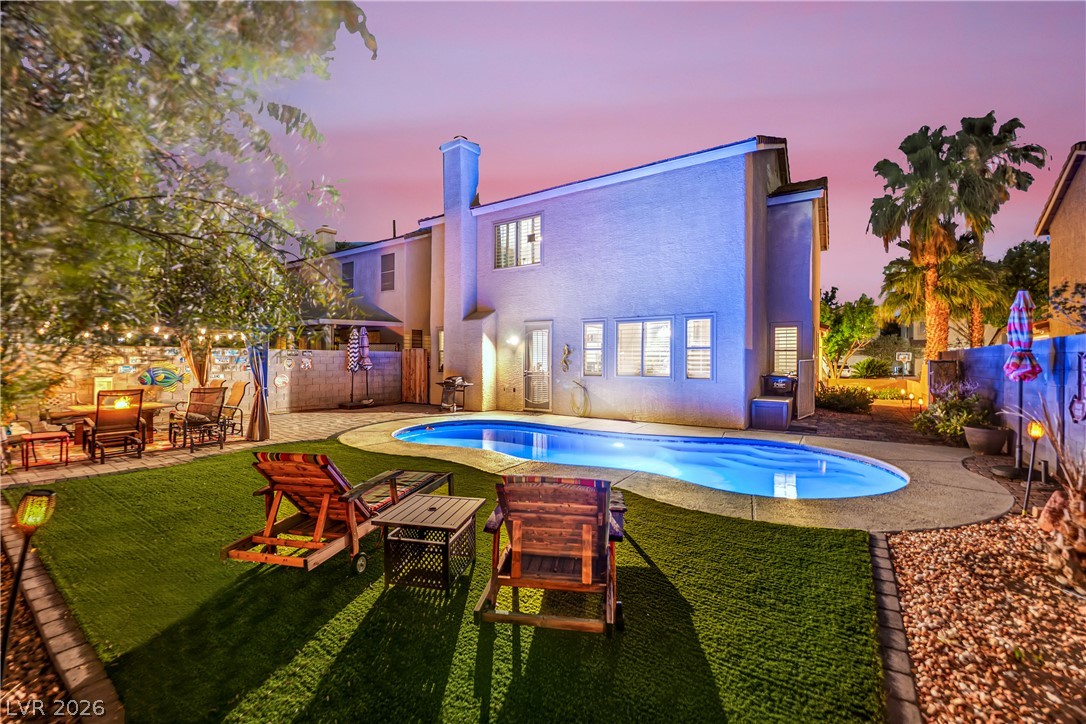 1724 Millstream Way Henderson, NV 89074 - Photo 51 of 60 An inviting backyard oasis offers a pristine pool and a cozy dining area, perfect for twilight gatherings.