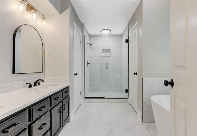 a spacious bathroom with a double vanity sink toilet mirror and shower