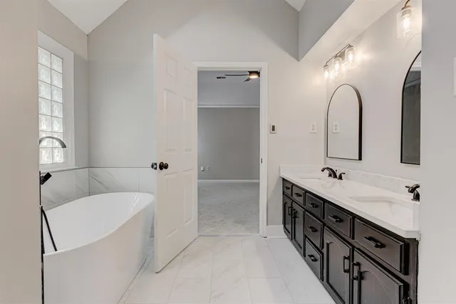 a bathroom with a double vanity sink mirror and bathtub