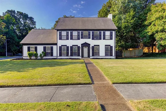 a view of a house with a big yard and large trees