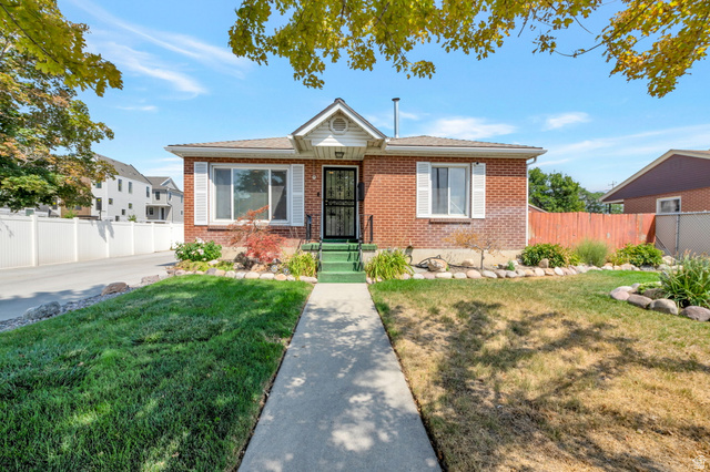 7391 Elm Street Midvale, UT 84047 - Photo 1 of 38 Brick exterior with white window shutters, a front porch, and a concrete walkway