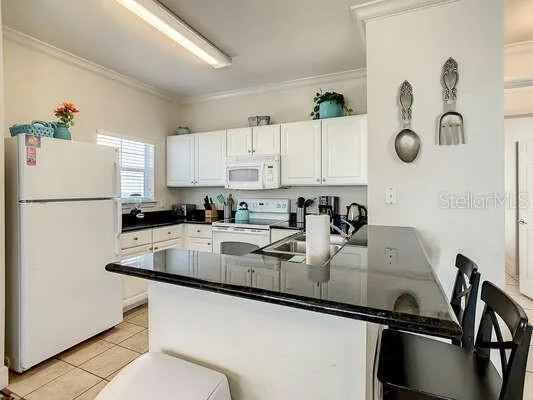 a kitchen with granite countertop white cabinets and refrigerator
