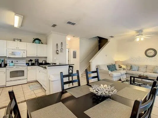 a kitchen with stainless steel appliances kitchen island granite countertop a dining table chairs and a refrigerator