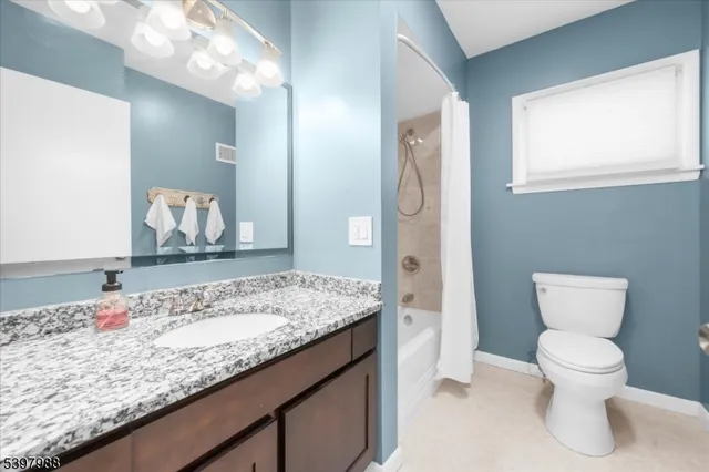 a bathroom with a granite countertop sink a toilet and a mirror