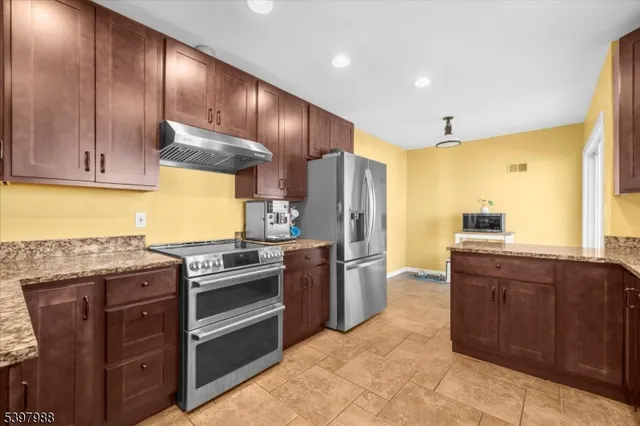 a kitchen with stainless steel appliances granite countertop wooden cabinets a stove top oven a sink and dishwasher