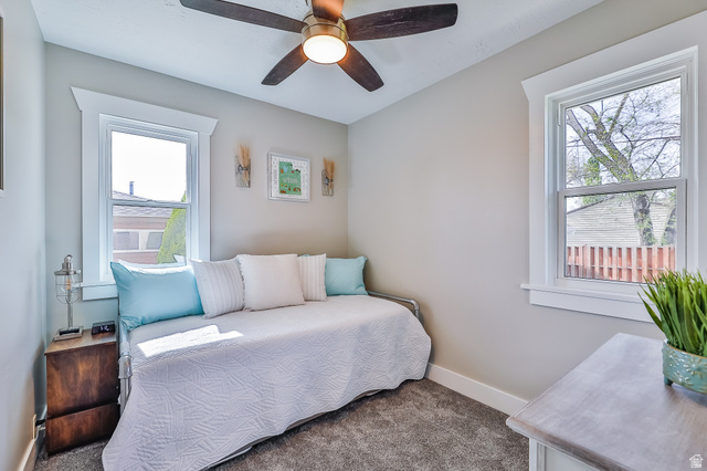 59 East 8680th Street South Sandy, UT 84070 - Photo 13 of 33 Carpeted room with a ceiling fan, two windows, and neutral wall paint