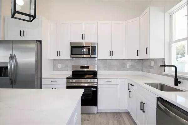a kitchen with kitchen island a sink stainless steel appliances and white cabinets