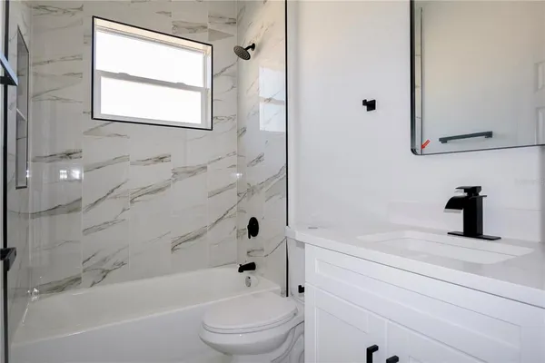 a bathroom with a bathtub shower sink vanity and toilet