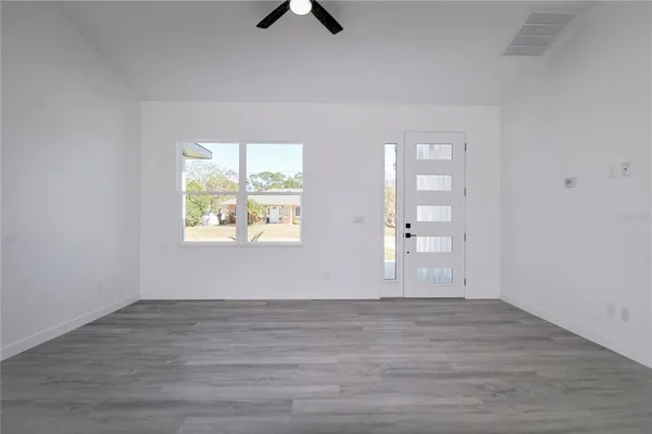 an empty room with wooden floor and windows