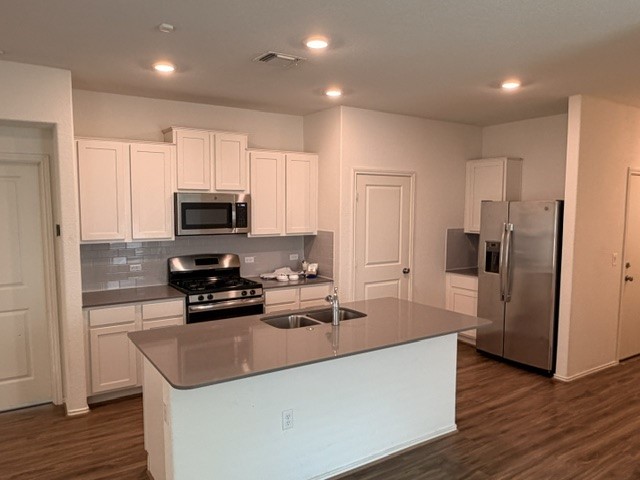 6917 Colorado Bluffs Road Austin, TX 78744 - Photo 2 of 19 a kitchen with kitchen island granite countertop a stove top oven a refrigerator a sink and dishwasher with wooden floor
