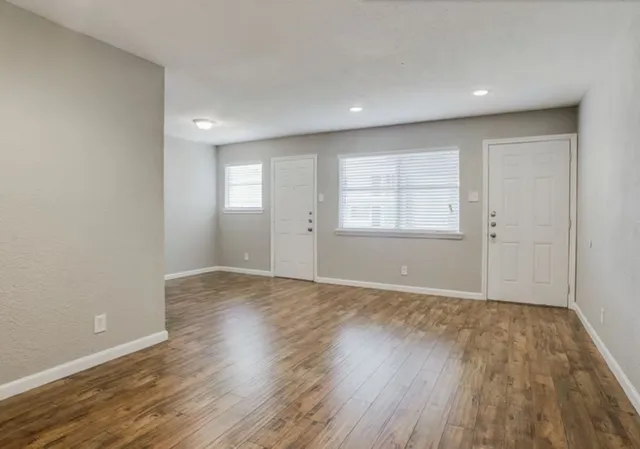 an empty room with wooden floor and windows