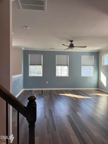 a view of an empty room with wooden floor and windows